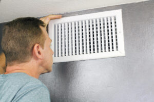 image of a man inspecting an air vent