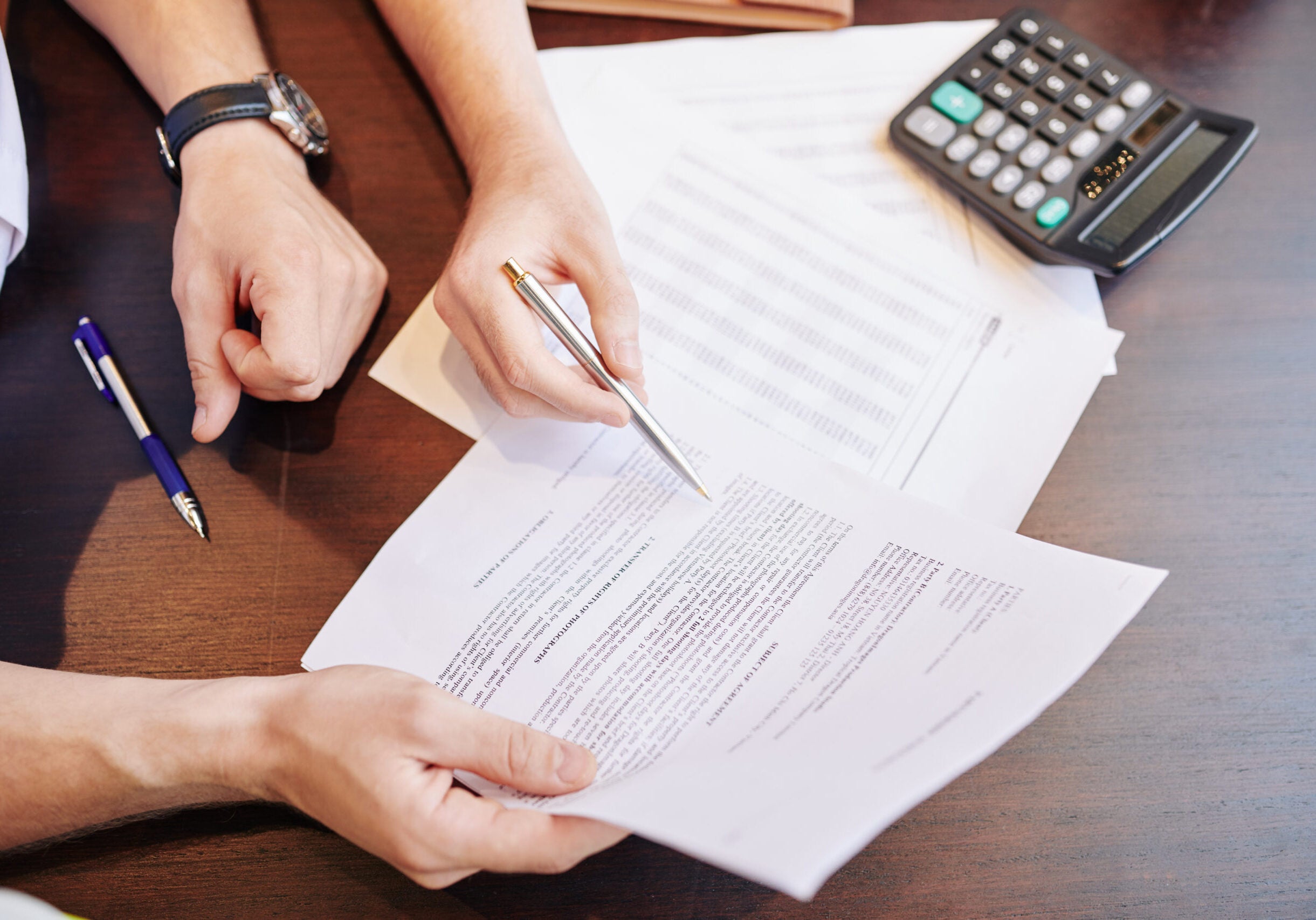 Businessmen checking partnership agreement Hands of businessmen checking every detail in document with partnership agreement at meeting